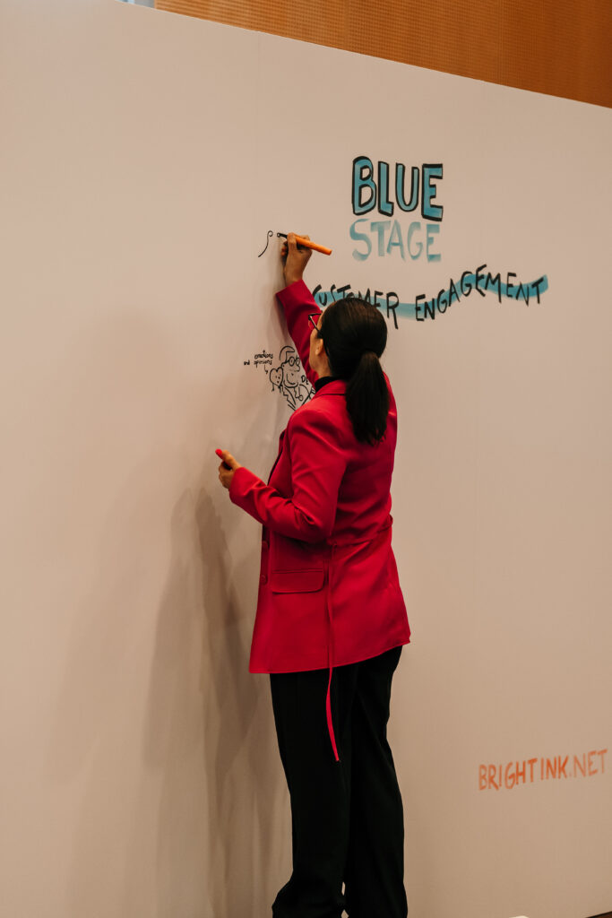 Graphic recording dibujante ilustrando en un mural gigante en congreso