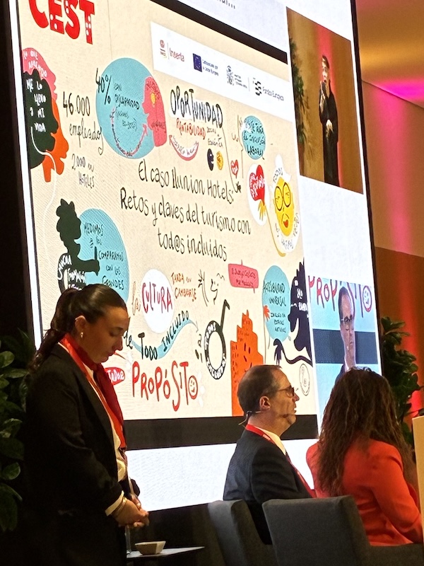 Marina Marisma durante una mesa redonda en CEST Mallorca, con la ilustración gráfica sobre turismo inclusivo proyectada en una pantalla de gran formato.