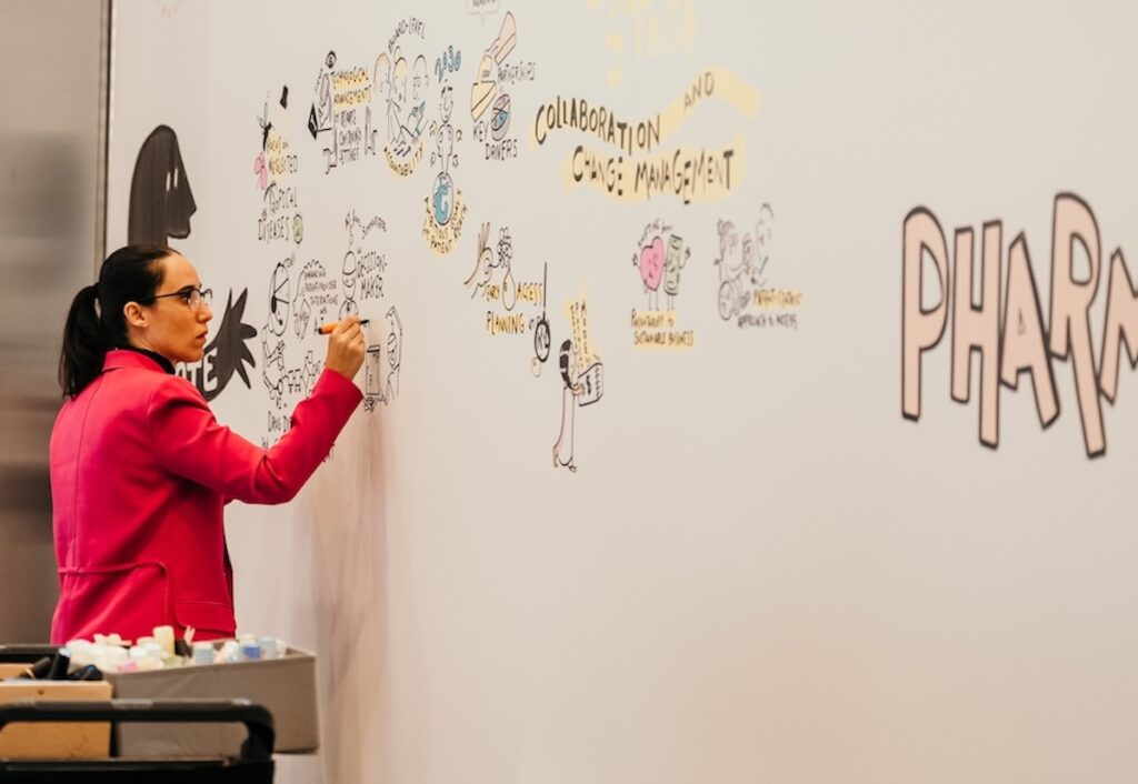 Marina Marisma realizando graphic recording en directo sobre una pared de gran formato durante un congreso farmacéutico en Barcelona.